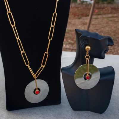 Parure 2 Pièces AMINA Un bijou fait main associant chaînes en mailles Trombones dorées, un pendentif disque en acier argenté et une breloque en strass de cristal rouge. Parfait pour toutes les occasions, apportant élégance et prestige.